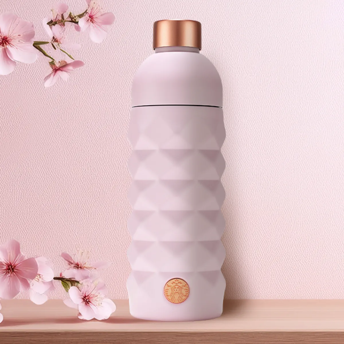 Diamond pattern Blush Pink coloured Bottle with rose gold accents - holds 16oz, on a table top with pink sakura background decoration