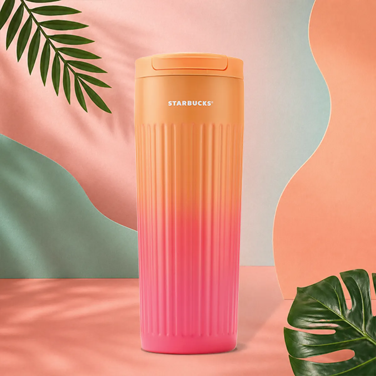 A photo of our new Peach Ombre tumbler, a soft peach (top) to uchsia (bottom) ombre colour combo, with a vertical striped texture, and a peach/orange click-lid.