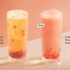 Two drinks - our summer sensation, Melon Pearl Starbucks Refresha drink with sweet melon flavour popping pearls - and now a blended version. Both sit on a table in front of a rich peach walled background.