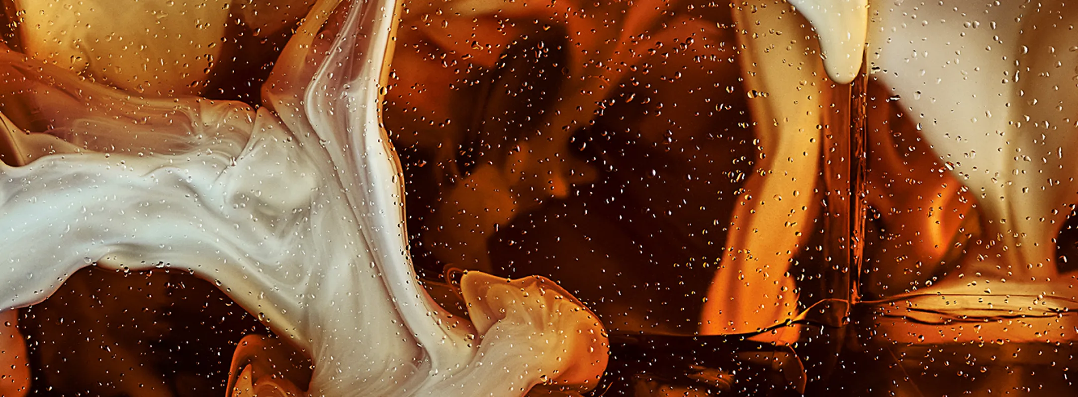 Cream cold foam swirls in black coffee, over ice.