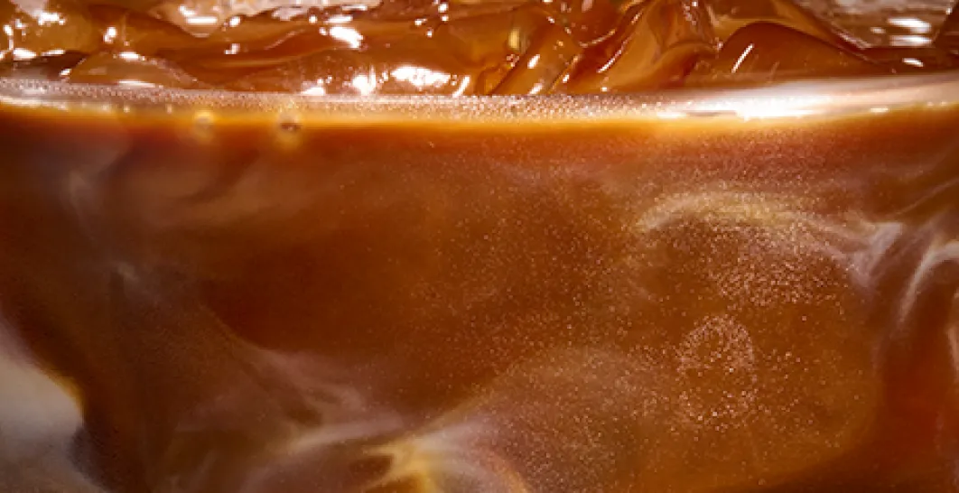 A close up photo of the top of an iced maple pecan macchiato with drizzle being added